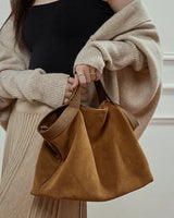 Person holding a brown suede handbag 